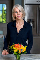 female nutrition coach standing at a kitchen counter with a boquet of flowers in front